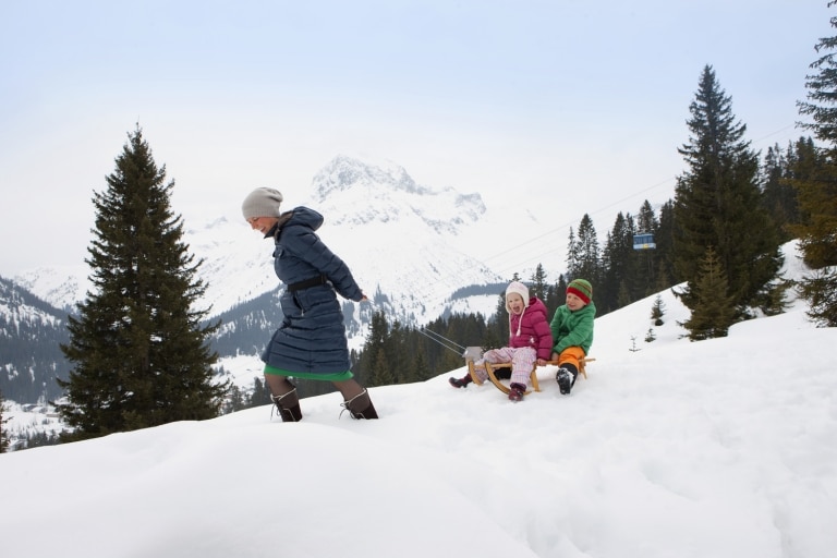 Symbolbild Rodeln in Österreich: eine Familie im Winterurlaub beim Rodeln in Österreich