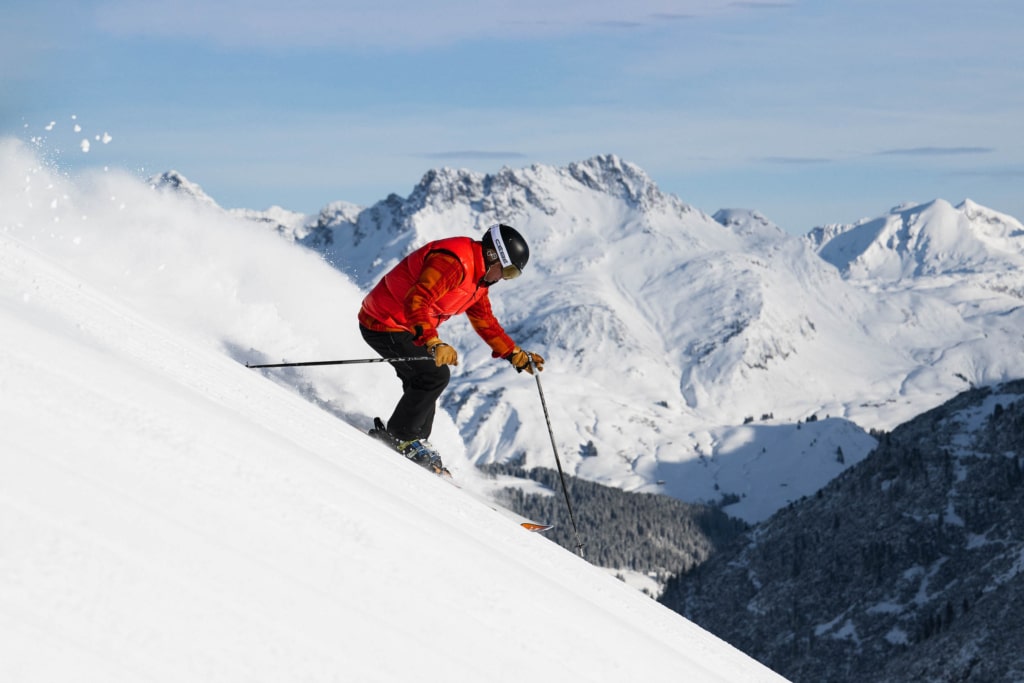 Skifahrer mit roter Jacke fährt im Steilhang im Skigebiet Lech Zürs